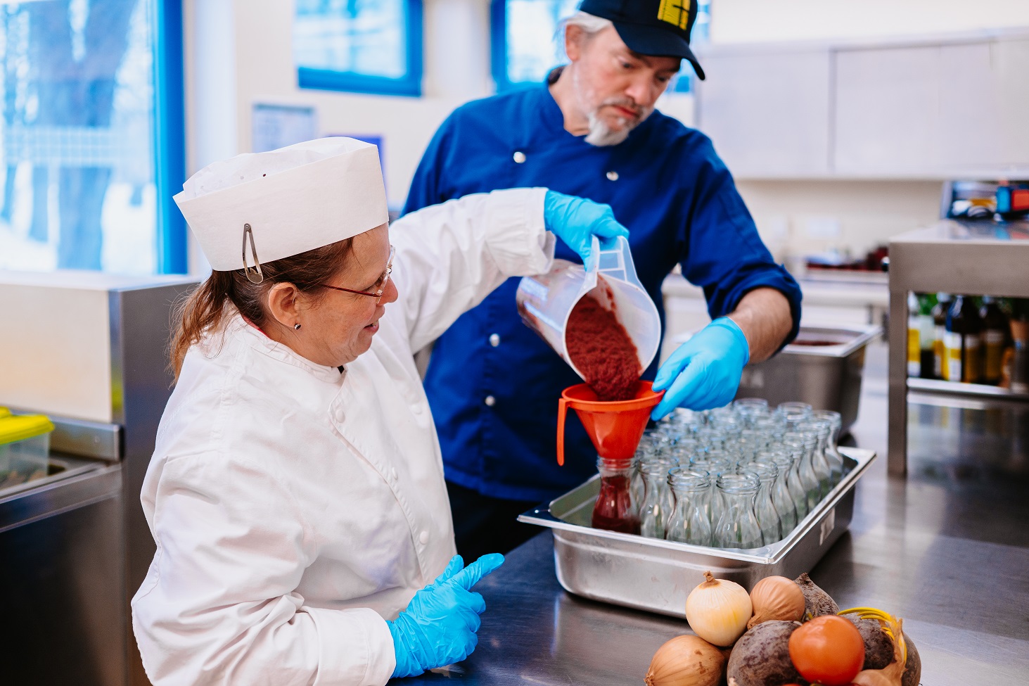 Eine Mitarbeiterin füllt frische Fruchtsoße in Glas ab